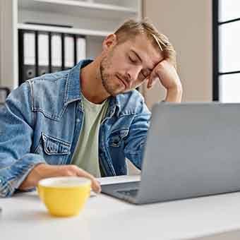 Young man falling asleep while at work because of sleep apnea