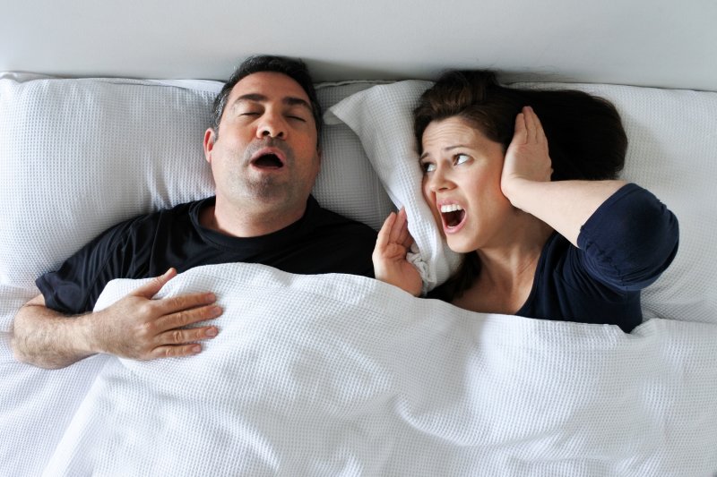 man snoring and woman covering her ears